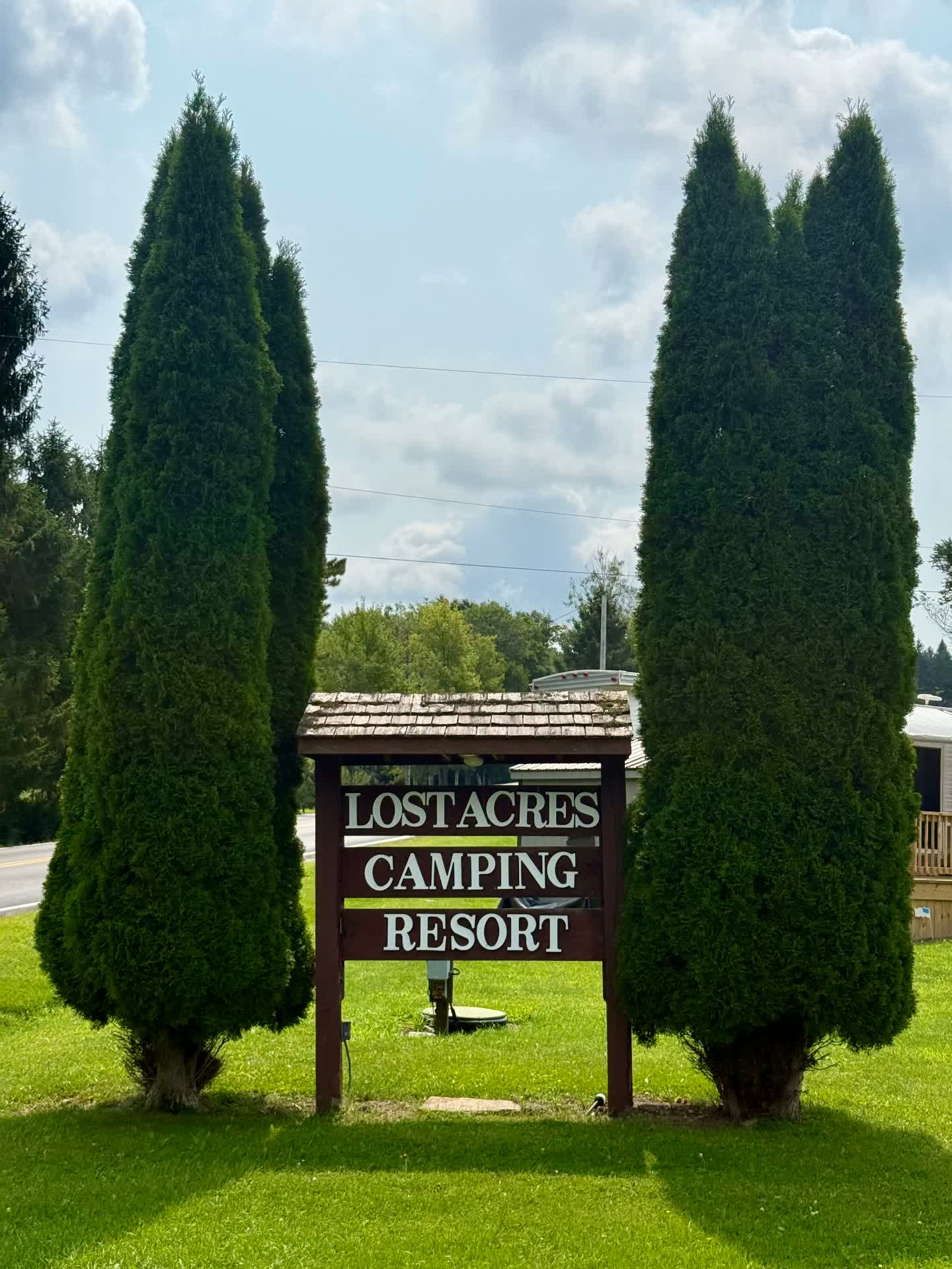 Lost Acres Camping Resort roadside sign framed by evergreens