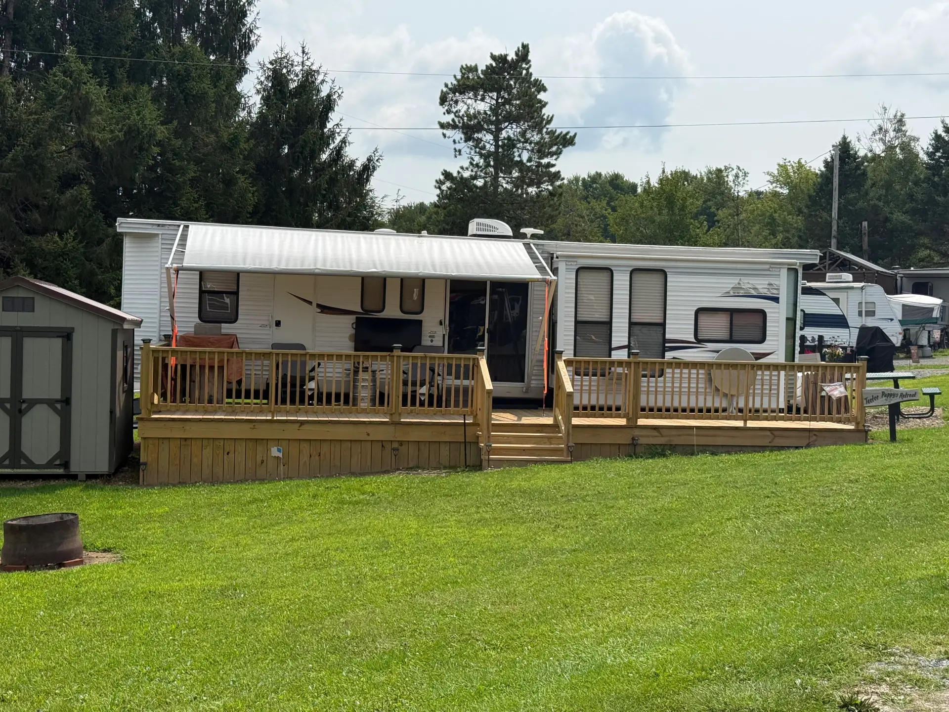 Camper with a wooden deck on a grassy site at Lost Acres